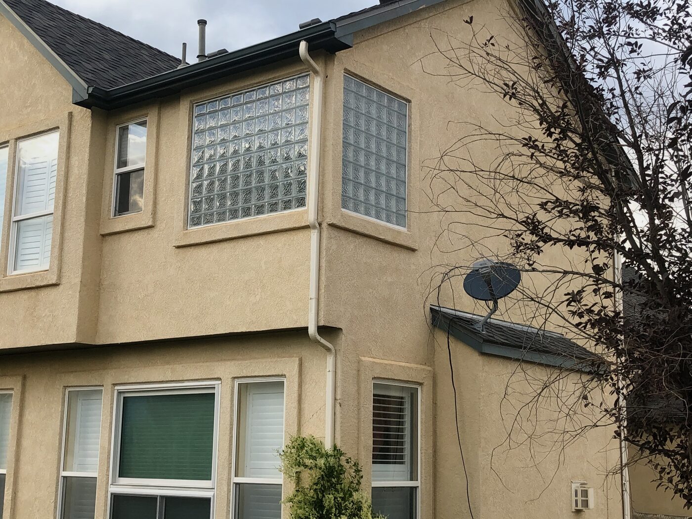 Corner glass block bay window on a two-story stucco home