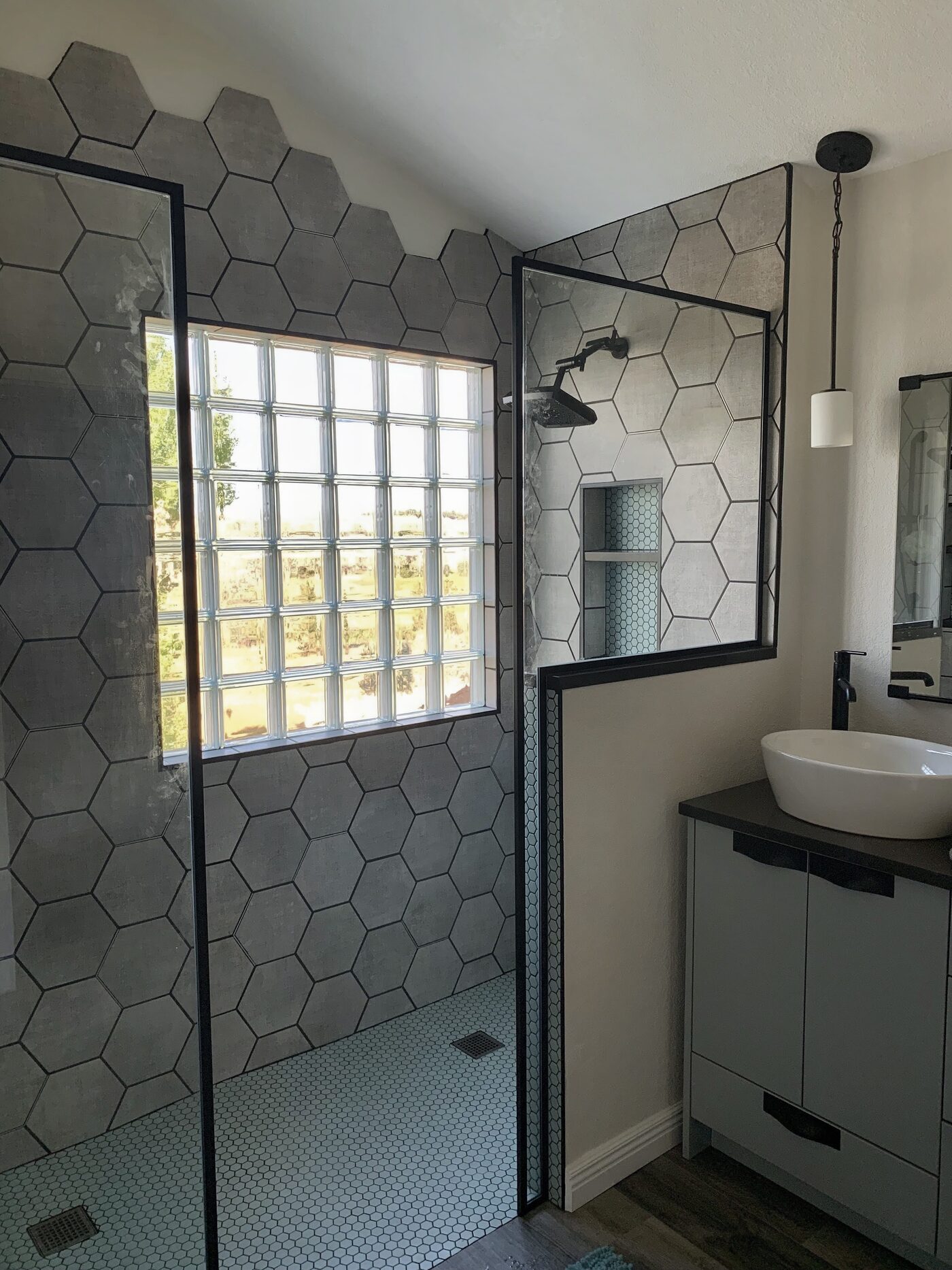Clear glass block window set into a gray hex-tile walk-in shower