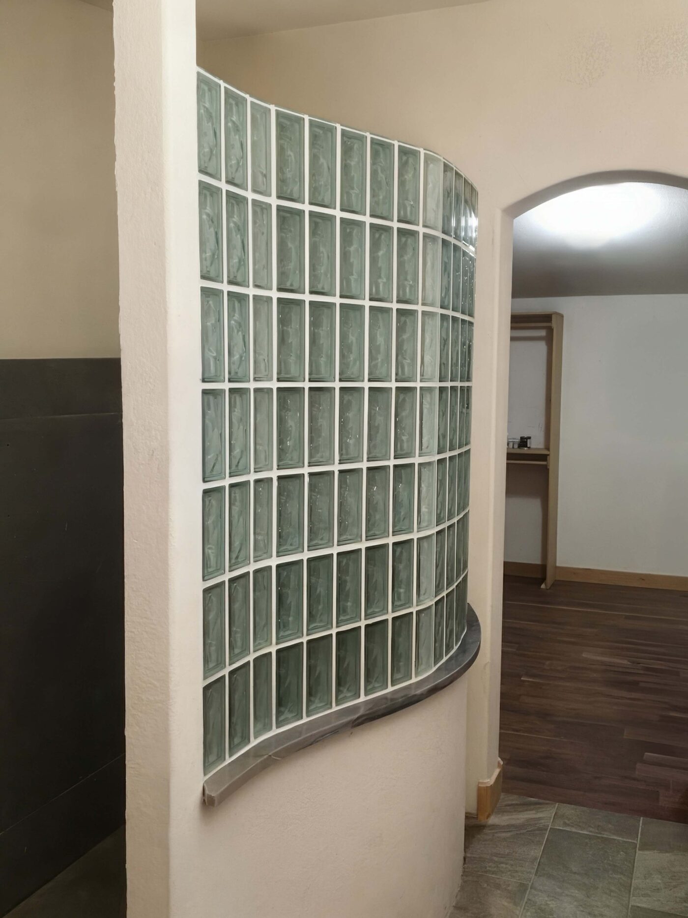 Curved interior partition built from green-tinted glass block